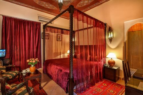 a bedroom with a canopy bed with red curtains at Riad & Spa Bahia Salam in Marrakech