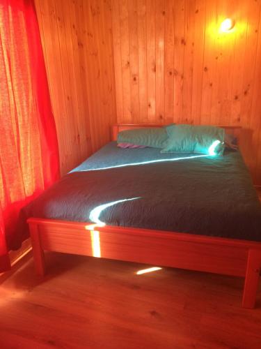 a bed in a room with a wooden wall at Cabaña Colibri in San Alfonso
