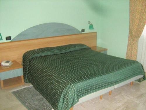 uma cama com um edredão verde num quarto em Motel Forum em Polla