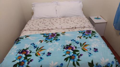 a bed with a floral comforter on it at Sossego da Casa Azul in Gramado