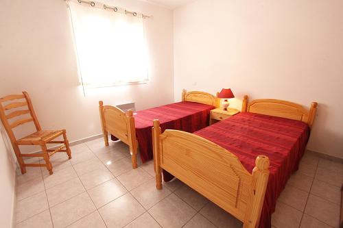 a bedroom with two beds and a chair and a window at Résidence Dicieppo in Ajaccio