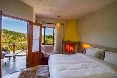 a bedroom with a bed and a fireplace and a balcony at Pousada Suiça Mineira Centro in Monte Verde