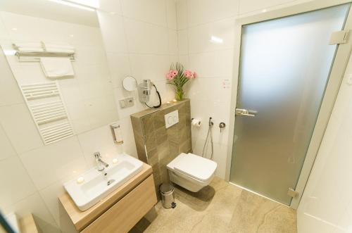 a white bathroom with a sink and a toilet at Garni hotel Castle Bridge in Český Krumlov
