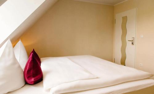 a bedroom with a white bed with a red pillow at My Place in Lautzenhausen