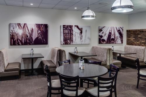 a restaurant with tables and chairs and paintings on the wall at Heritage Inn Hotel & Convention Centre - Taber in Taber