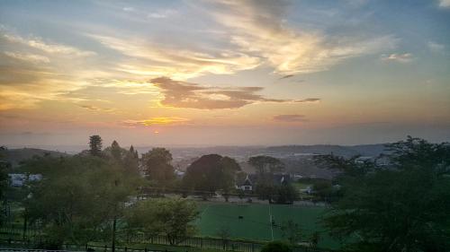 a sunset over a field with a house and trees at Southey House in Kloof