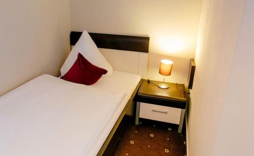 a small room with a bed with a red pillow on it at My Place in Lautzenhausen