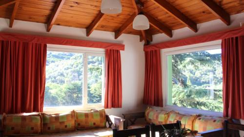 a room with two windows with red curtains at Terrazas de Cruz Chica. in La Cumbre