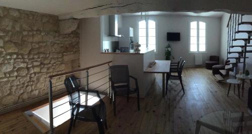 uma sala de estar com cadeiras, uma mesa e uma escada em L'appart des Jacobins em Saint-Émilion