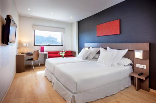 una camera d'albergo con 2 letti, una scrivania e una TV di Allegro Granada a Granada