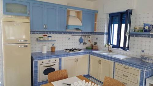 a blue and white kitchen with a table and a refrigerator at Casa MARESOLE in Mattinata