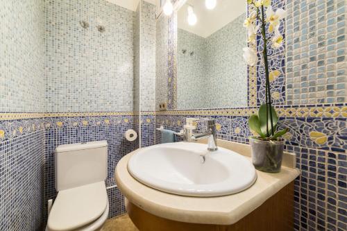 een badkamer met een wastafel, een toilet en een spiegel bij El Jardín del Ángel Yolka in Madrid