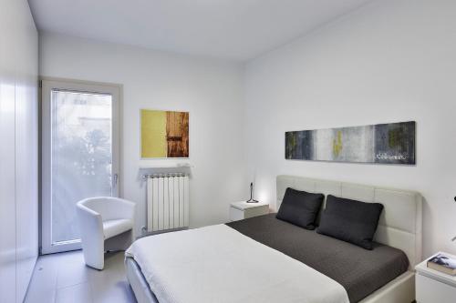 ein weißes Schlafzimmer mit einem Bett und einem weißen Stuhl in der Unterkunft Casetta sul mare A in Monopoli