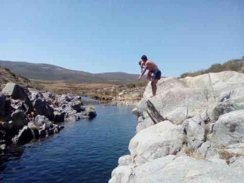 a man standing on a rock next to a river at Los Arroyos in San Martín de la Vega del Alberche