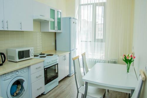 a white kitchen with a table and a microwave at Apartments Manghilik El 53/66 in Astana