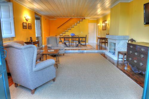 a living room with chairs and a table and a fireplace at Quinta de Luou in Santa Cruz do Lima