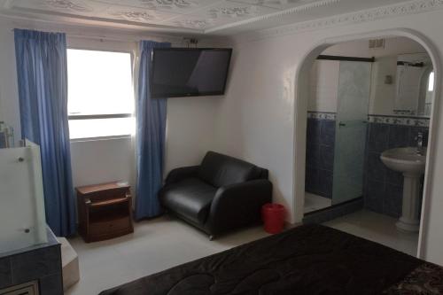 1 dormitorio con silla negra y lavamanos en Motel Piramides De Cristal, en Bogotá