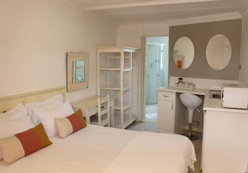 a bedroom with a white bed and a kitchen at Golden Key Guesthouse in Vredenburg