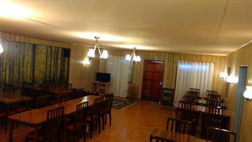 a dining room with tables and chairs and a television at La Posada de Pinky Hotel in Puerto Santa Cruz