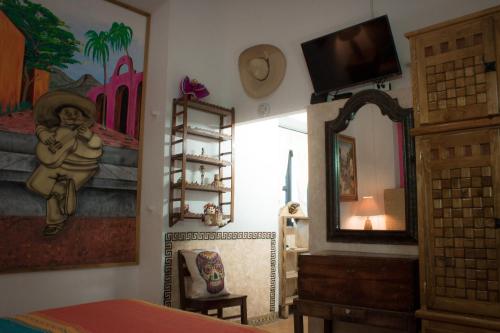 1 dormitorio con espejo y una pintura en la pared en Casona Tlaquepaque Temazcal & Spa, en Guadalajara