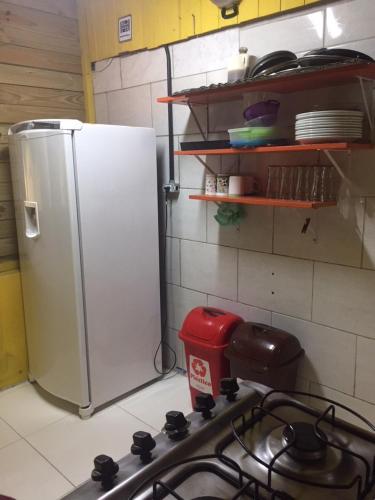 a kitchen with a white refrigerator and a stove at Hostel Encantadas Ecologic in Ilha do Mel