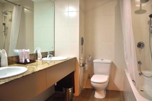 a bathroom with a toilet and a sink and a mirror at Ramada Katunayake in Katunayaka