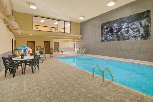 a pool in a hotel with a table and chairs at Rushmore Express & Suites in Keystone