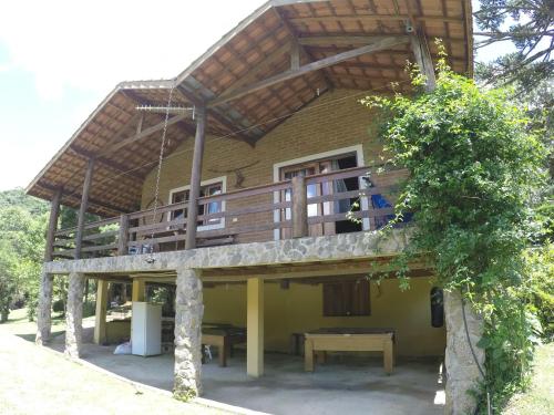 a house with a balcony and a table on it at Sitio Rosa de Minas in Gonçalves