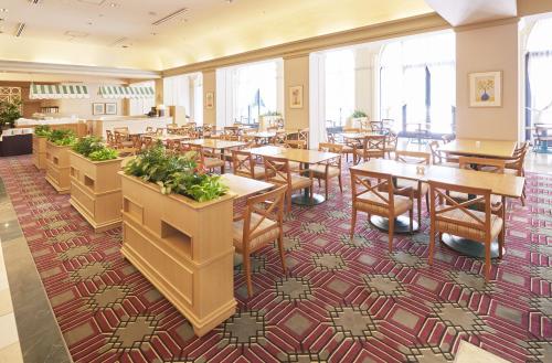 a dining room with tables and chairs and windows at Hotel Okura Tokyo Bay in Urayasu