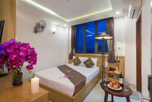 a bedroom with a bed and a table with flowers at Trang Ngan Hotel by THG in Danang