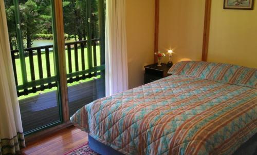 1 dormitorio con cama y vistas a un balcón en Hawke Brook Chalets en Pemberton