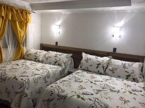 a bedroom with two beds and two lights on the wall at Residencial Victoria Said in Linares