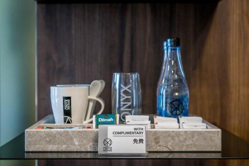 a shelf with cups and a glass bottle on it at Onix Hotel Bangkok in Bangkok