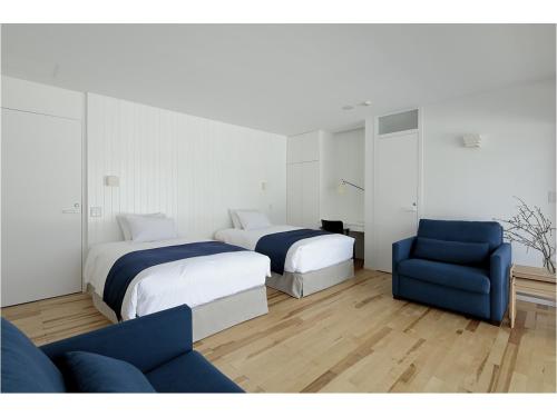 una habitación de hotel con 2 camas y una silla azul en Wakkanupuri, en Teshikaga