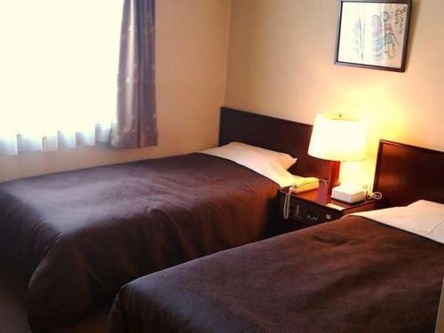 une chambre d'hôtel avec deux lits et une lampe dans l'établissement Select Inn Hamamatsu Ekimae, à Hamamatsu
