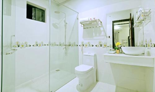 a white bathroom with a toilet and a sink at Daisy Garden Villa Hoi An in Hoi An
