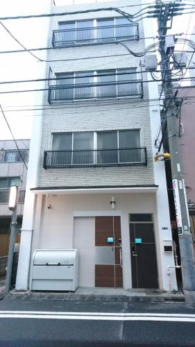 a white building with a balcony on a street at Rimon Apartment in Tokyo