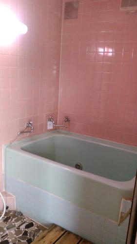 La salle de bains est pourvue d'une baignoire et de carrelage rose. dans l'établissement Minshuku Takahashi Kashibuneten, à Maisaka