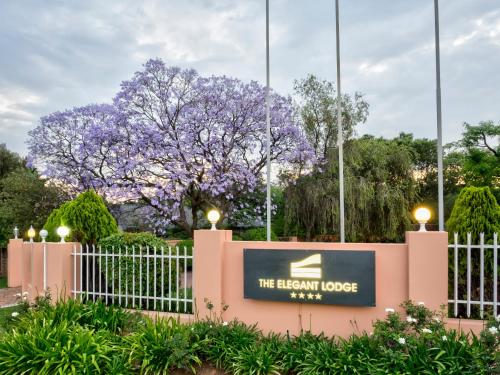 a sign for the elephant house with a flowering tree in the background at The Elegant Lodge Menlo Park in Pretoria