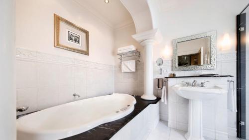 Baño blanco con bañera y lavamanos en Craig's Royal Hotel en Ballarat