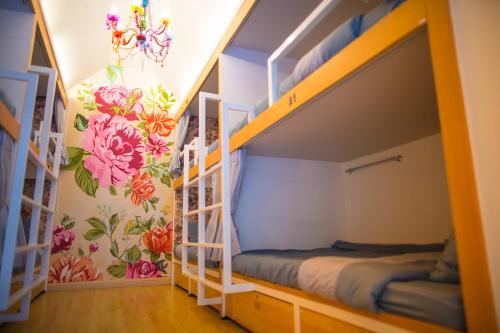 a room with bunk beds with flowers on the walls at Chiangmai Midpoint Activity Hostel in Chiang Mai