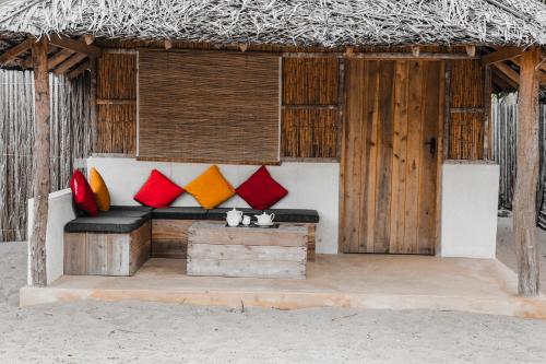 a bench with colorful pillows in a straw hut at Sandy Edge in Kalpitiya