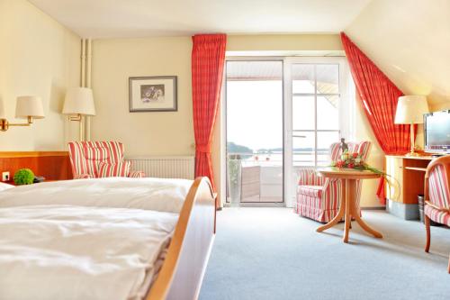 a hotel room with a bed and a balcony at Strauers Hotel am See in Bosau