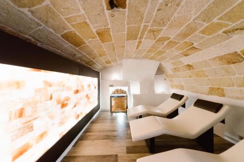 ポリニャーノ・ア・マーレにあるGiovì Relaisの白い椅子と石の天井が特徴の客室