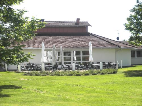 a white house with tables and chairs and umbrellas at Hotell Erikslund in Ängelholm