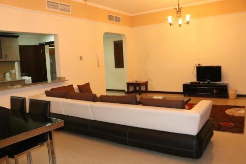 a living room with a white couch and a tv at Marina Tower in Juffair