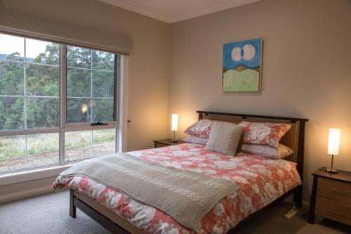 una camera da letto con un letto e due finestre di Mountain Blue Guest House a Deloraine