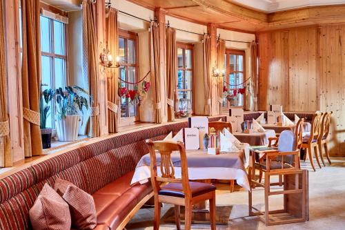 a restaurant with tables and chairs and windows at Habachklause Familien Bauernhof Resort in Bramberg am Wildkogel
