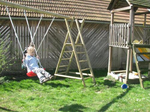 a young child sitting on a swing in a yard at Bauernhof Flucher-Plaschg in Straden