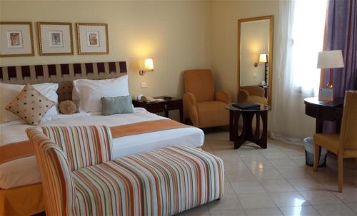 a hotel room with a bed and a chair at Seashell Julai'a Hotel & Resort Family resort in Al Qulay‘ah